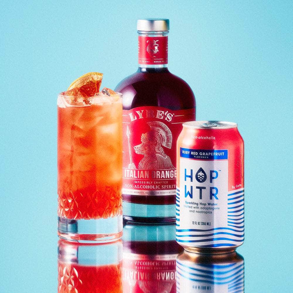 HOPWTR Ruby Red Grapefruit can beside a citrus mocktail and non-alcoholic spirit