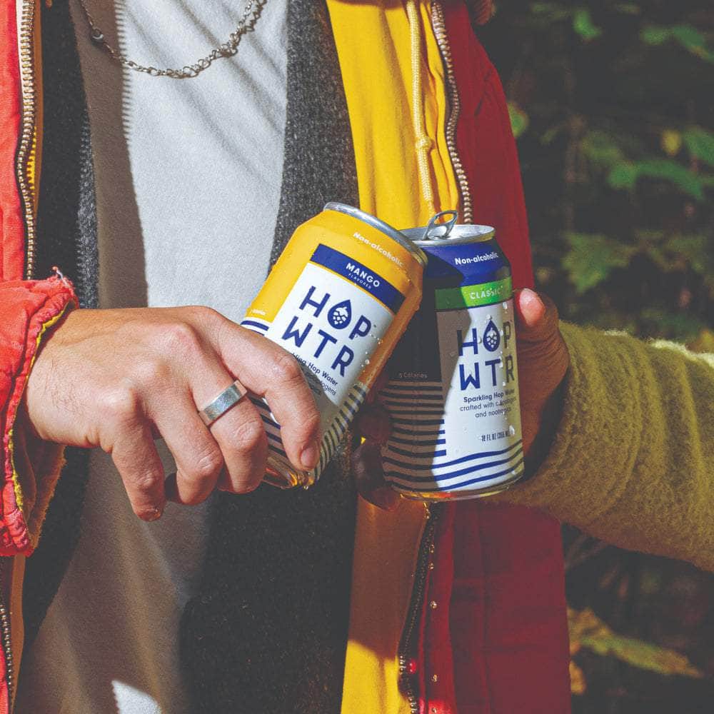 People holding HOPWTR Mango and Classic cans outdoors